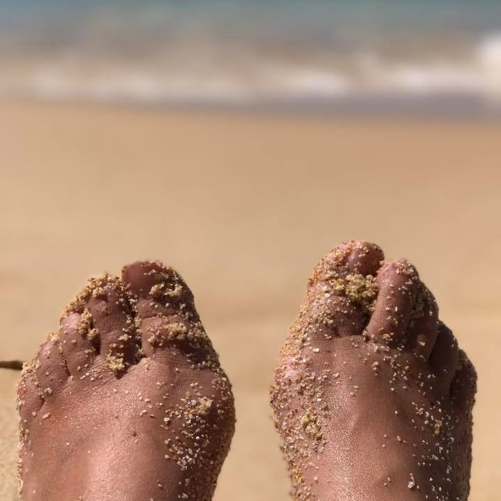 Sandy toes against a beach and sea
