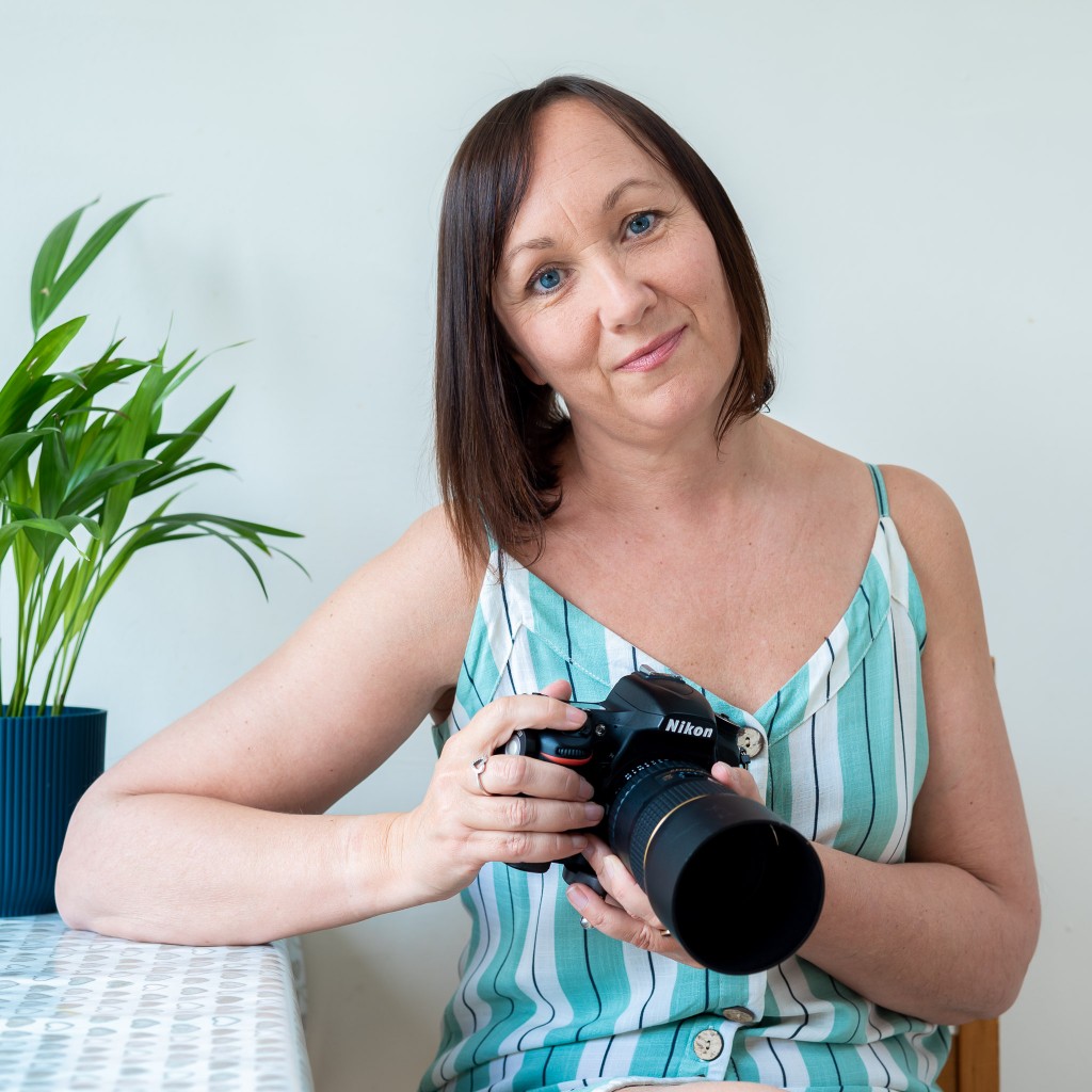 Brand photographer image with teal and white striped dress and Nikon camera